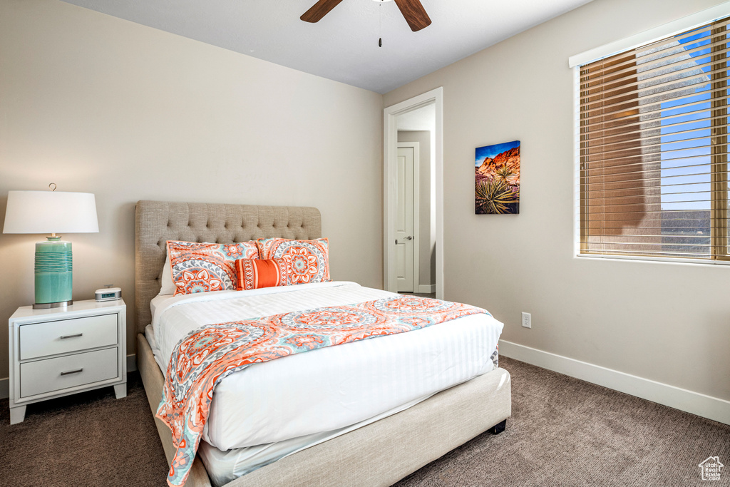 Bedroom featuring dark carpet, baseboards, and ceiling fan