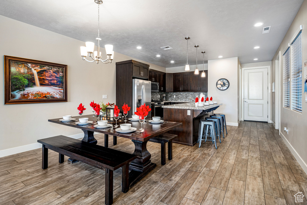 Dining area with light wood-style floors, baseboards, a chandelier, and recessed lighting