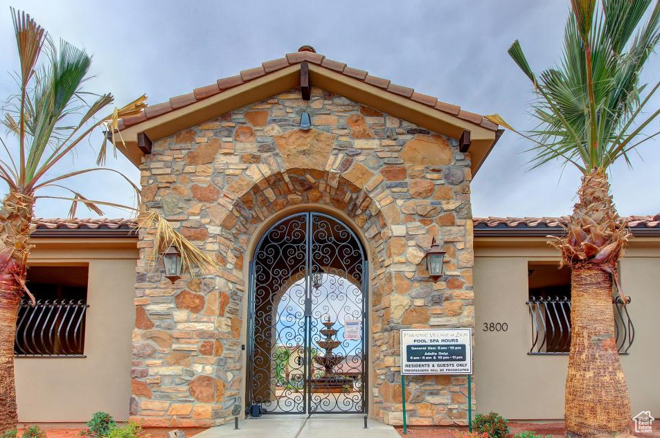 Property entrance featuring a tiled roof, stone siding, and stucco siding