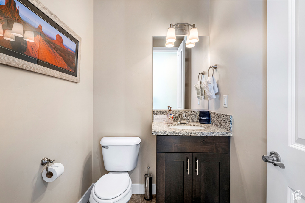 Bathroom with toilet, vanity, and baseboards