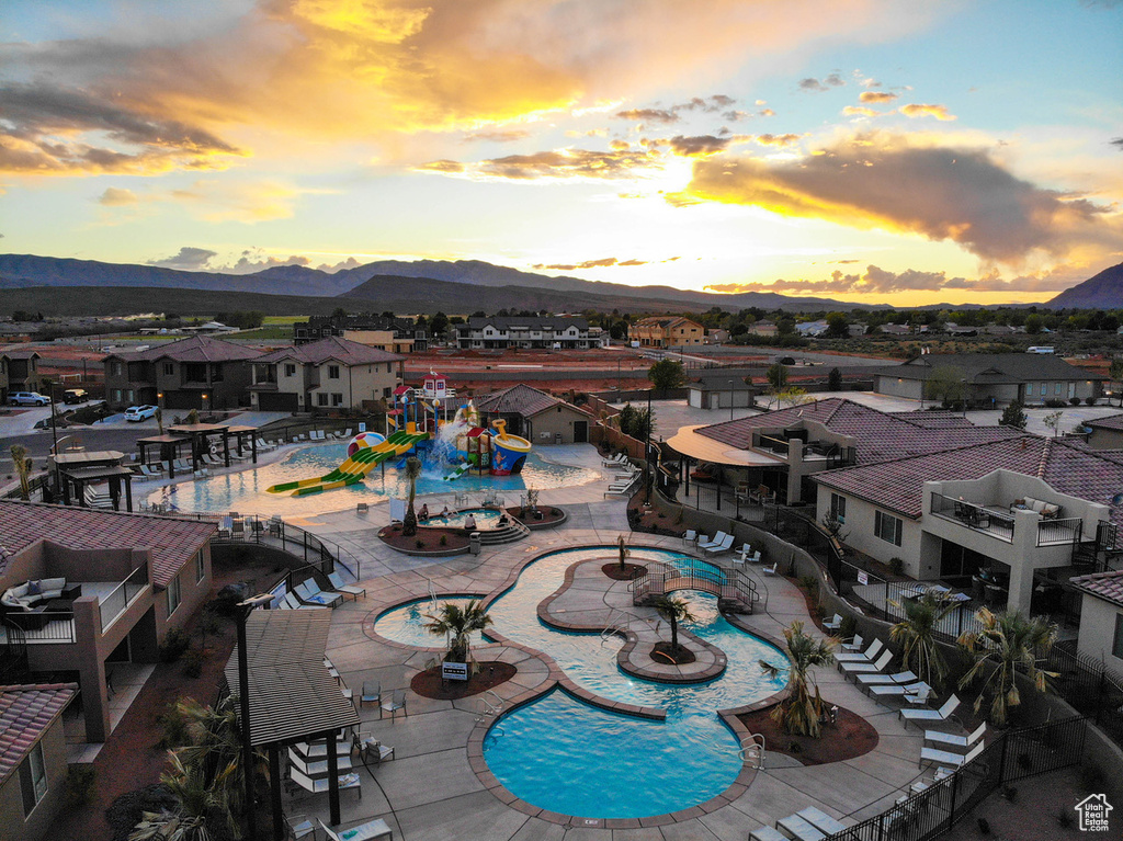 Pool at dusk featuring a mountain view, a community pool, a patio area, and a residential view