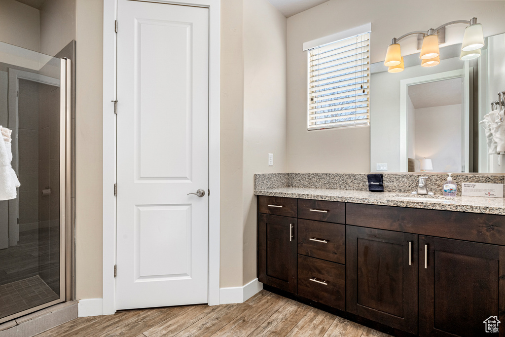 Bathroom featuring a shower stall, wood finished floors, vanity, and baseboards