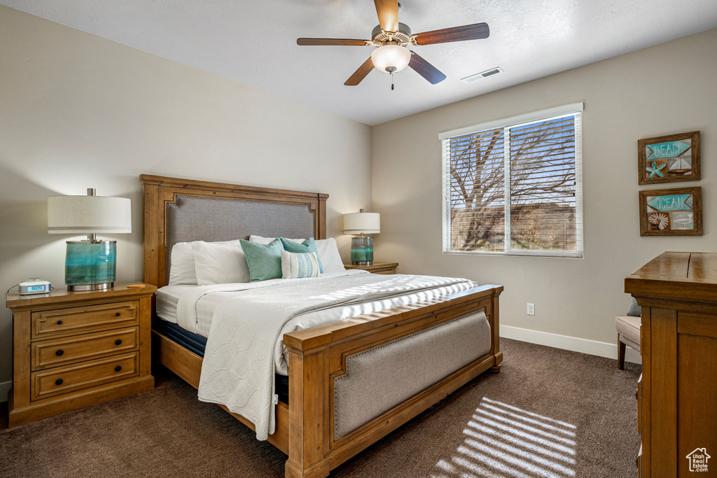 Bedroom featuring dark carpet, baseboards, and a ceiling fan