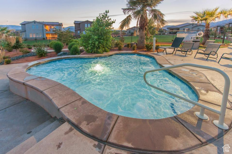 Pool at dusk featuring a patio and a fenced backyard