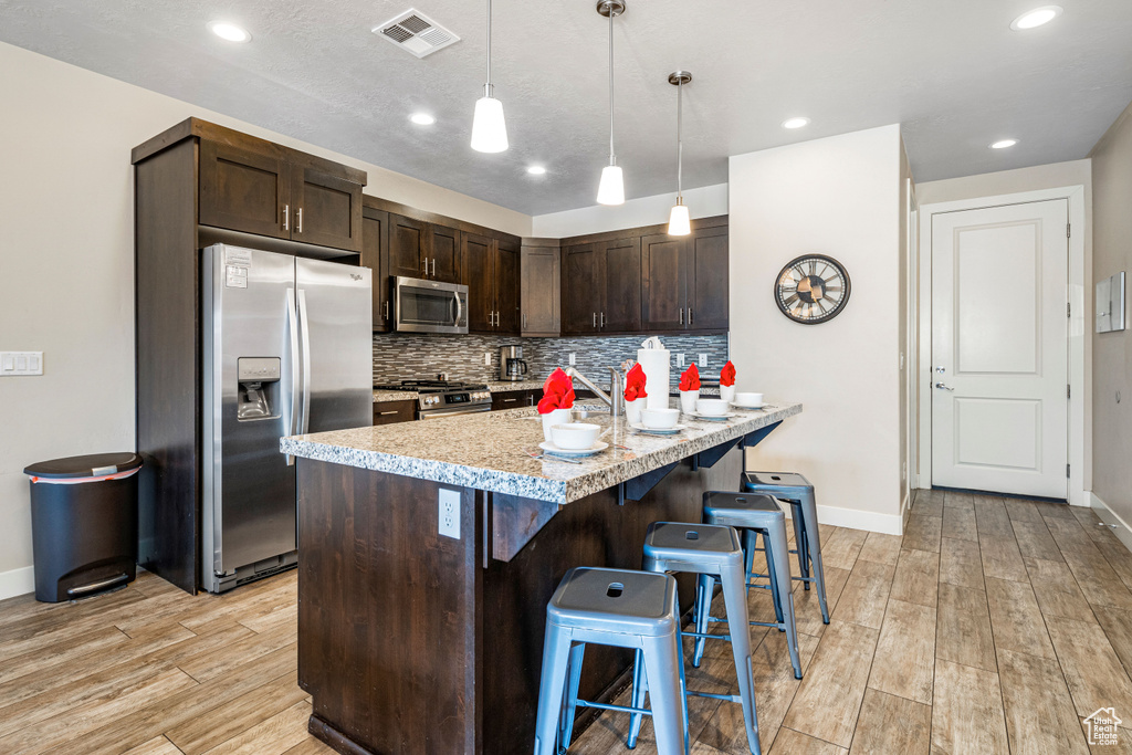 Kitchen featuring stainless steel appliances, light wood-style flooring, dark brown cabinetry, baseboards, and recessed lighting
