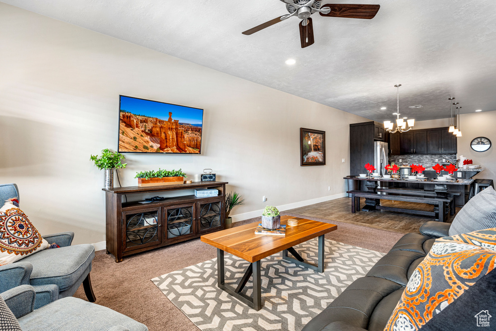 Living room with a chandelier, a ceiling fan, light carpet, baseboards, and recessed lighting