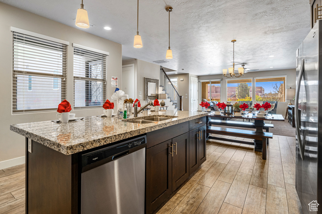 Kitchen with stainless steel appliances, a sink, light wood-style flooring, a chandelier, and recessed lighting