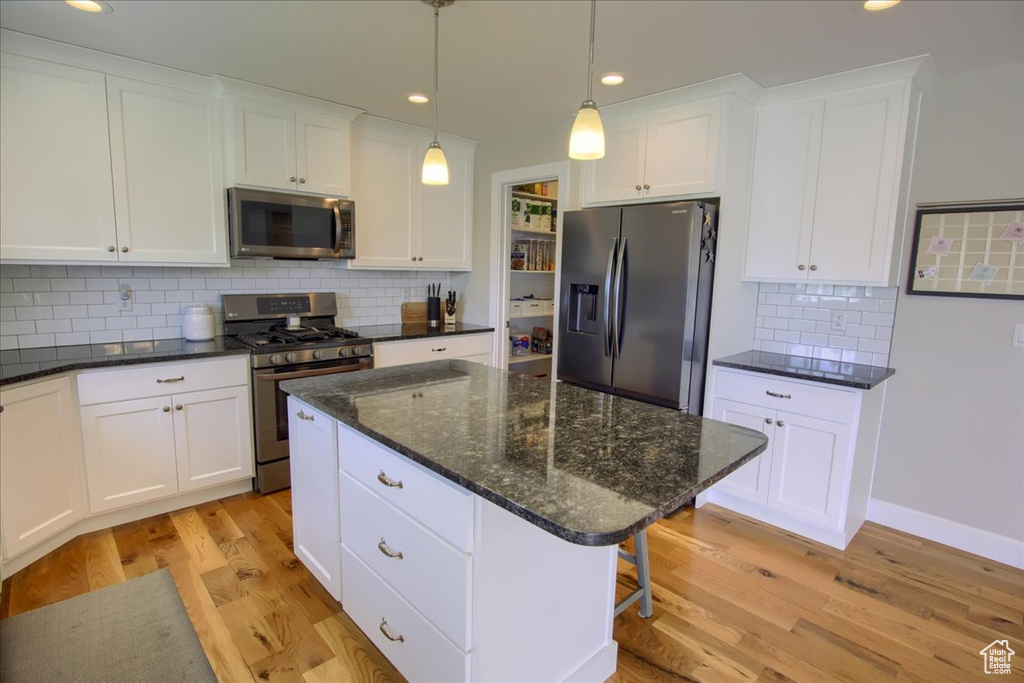 Kitchen featuring stainless steel appliances, light wood-type flooring, white cabinets, backsplash, and recessed lighting