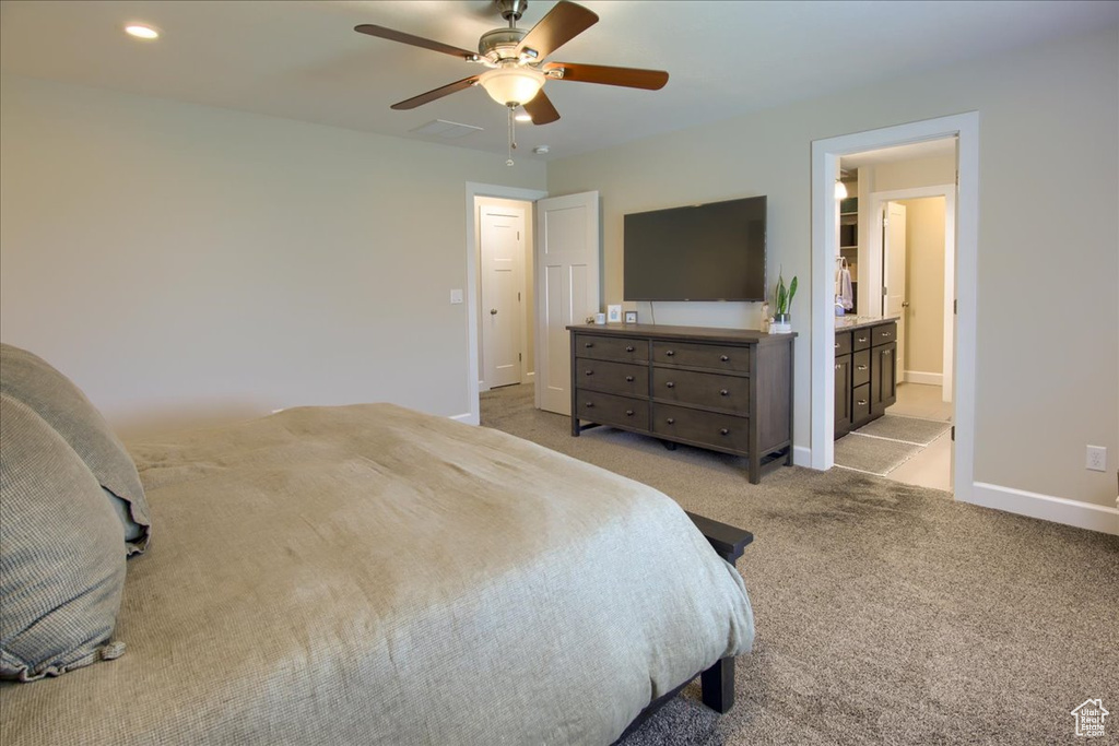 Bedroom featuring light colored carpet, baseboards, ensuite bath, and ceiling fan