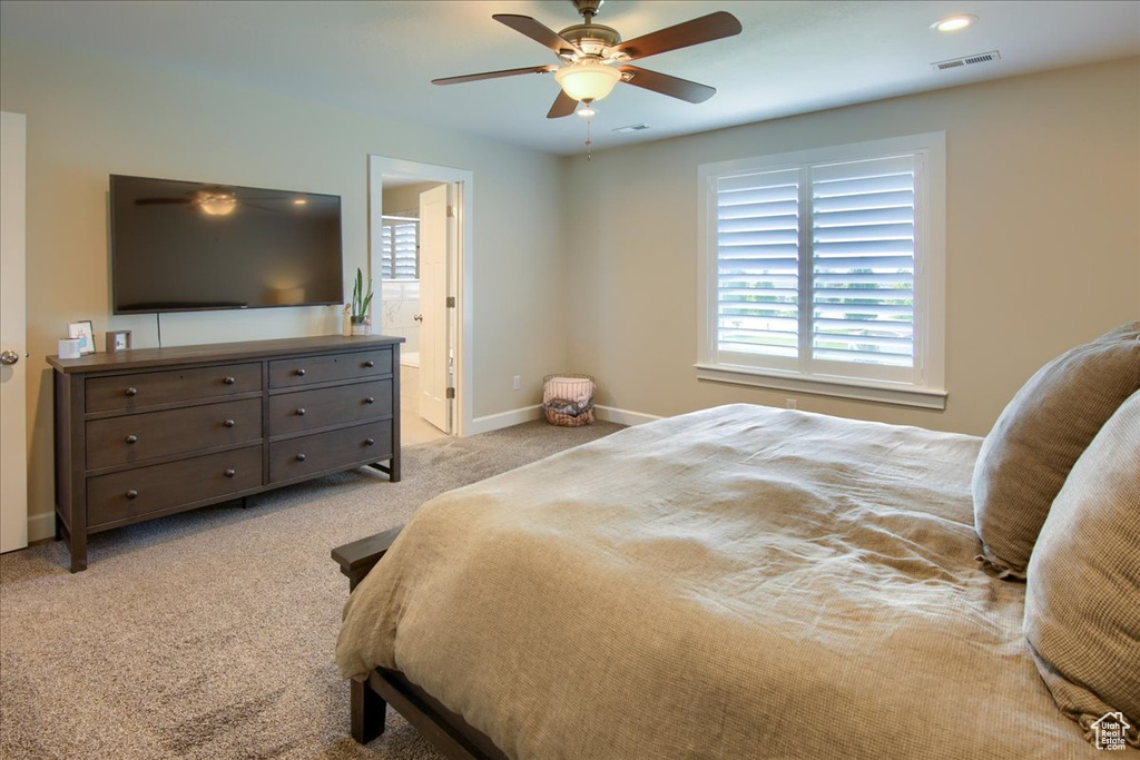 Bedroom with light carpet, baseboards, a ceiling fan, and ensuite bathroom