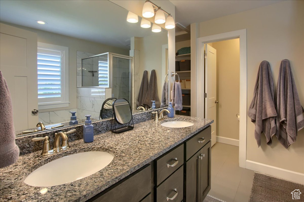 Bathroom featuring a stall shower, double vanity, and tile patterned floors
