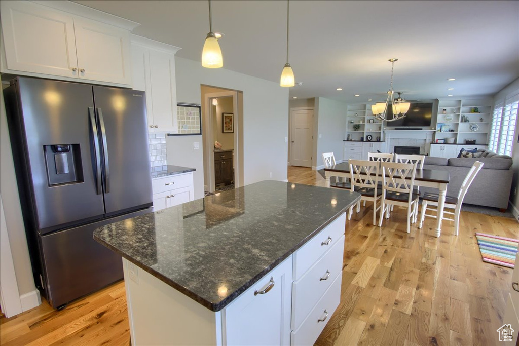 Kitchen with stainless steel fridge, light wood-type flooring, backsplash, white cabinetry, and recessed lighting