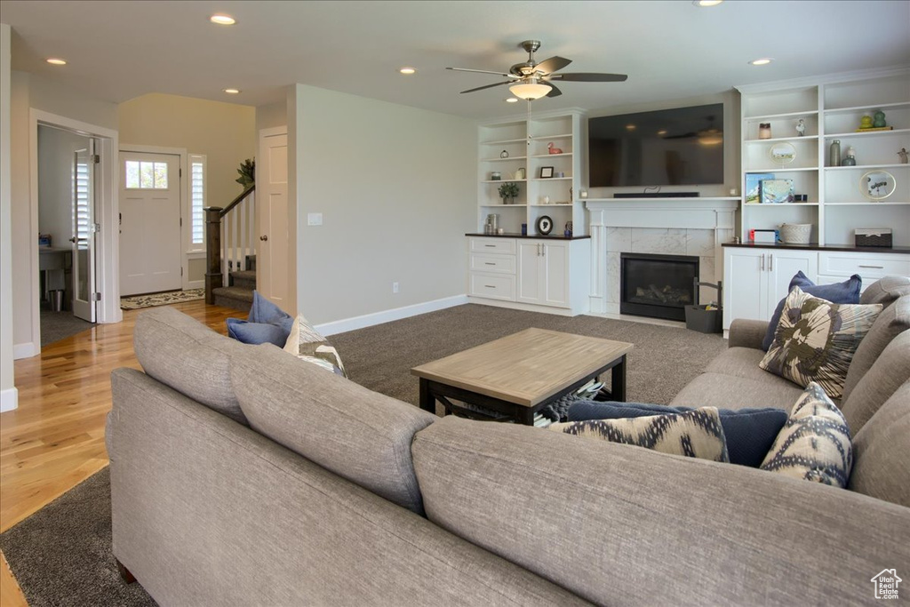 Living room with stairway, baseboards, ceiling fan, a high end fireplace, and recessed lighting