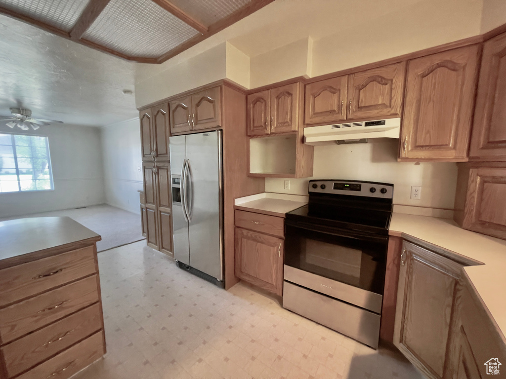 Kitchen with stainless steel appliances, under cabinet range hood, light floors, ceiling fan, and light countertops