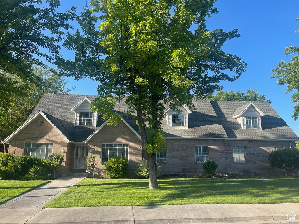 Traditional-style home with brick siding, a front lawn, and roof with shingles
