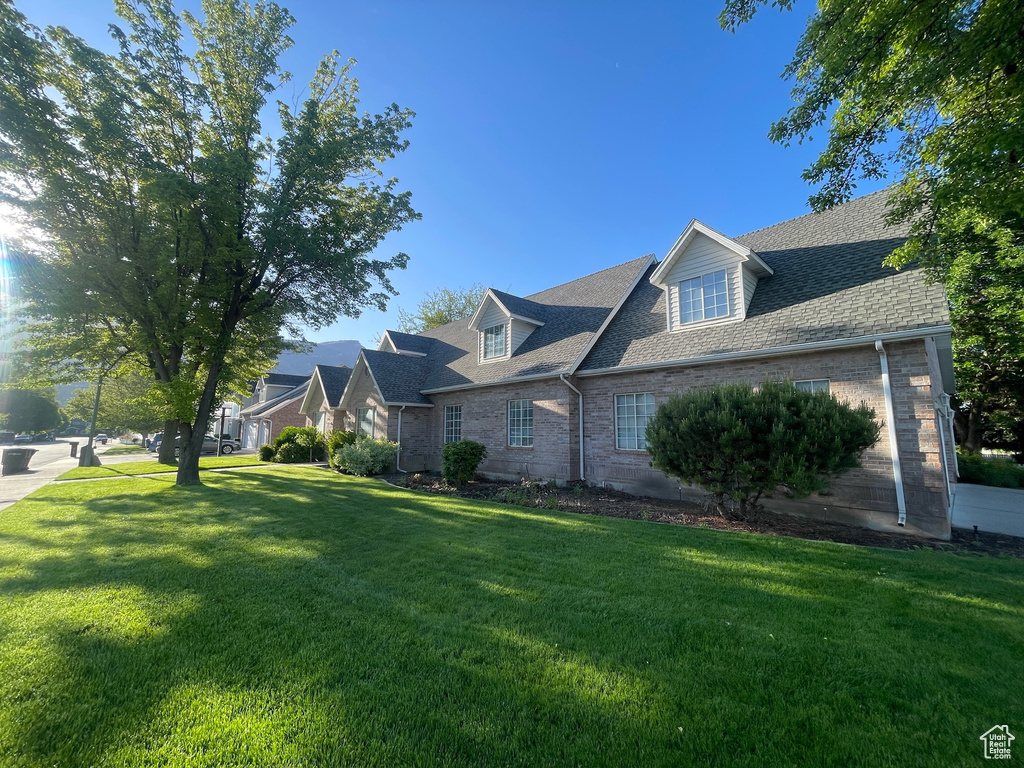 View of front of house featuring brick siding, a front lawn, and roof with shingles