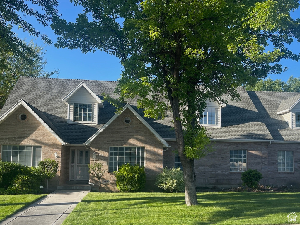 Traditional home featuring brick siding, a front lawn, and roof with shingles