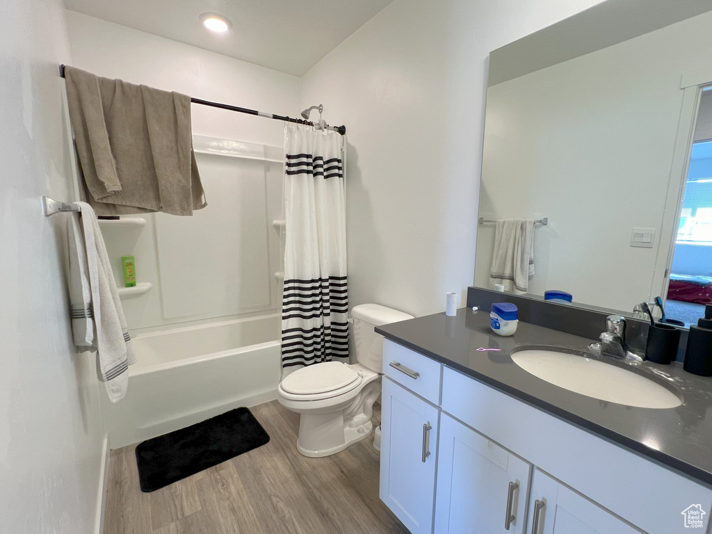 Bathroom featuring wood finished floors, vanity, toilet, and shower / tub combo