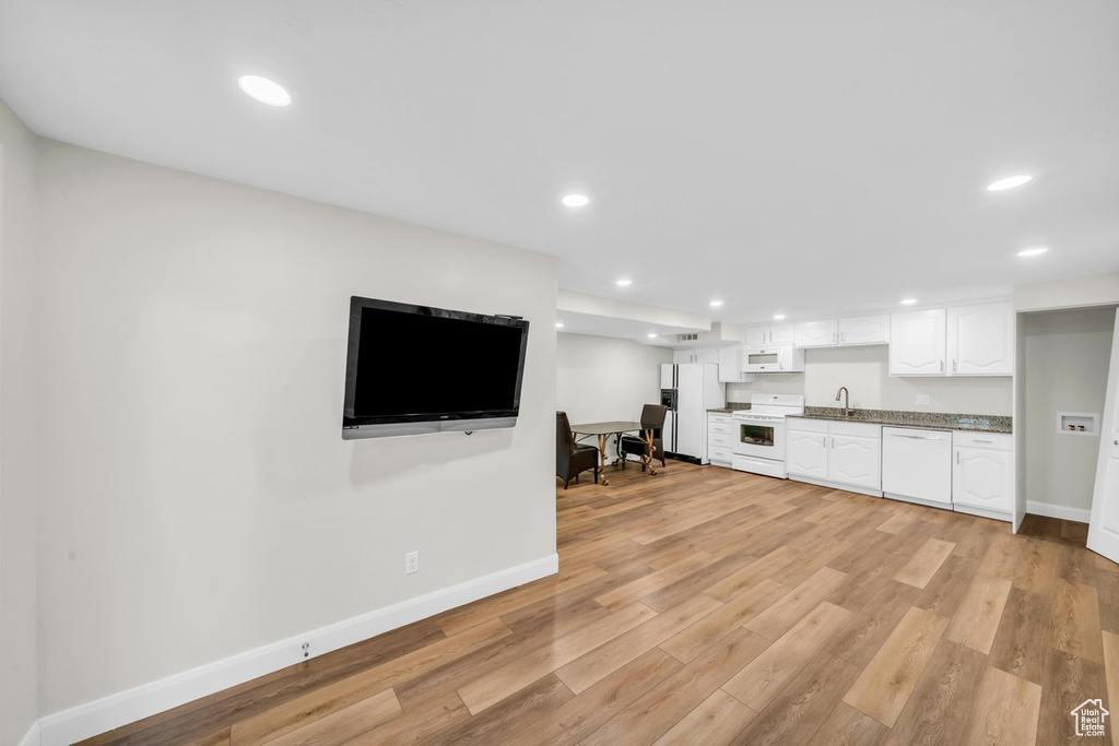 Unfurnished living room with a sink, baseboards, light wood-style flooring, and recessed lighting