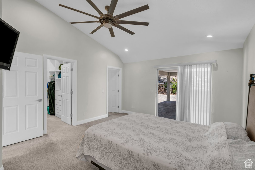 Bedroom with lofted ceiling, light carpet, a walk in closet, recessed lighting, and baseboards