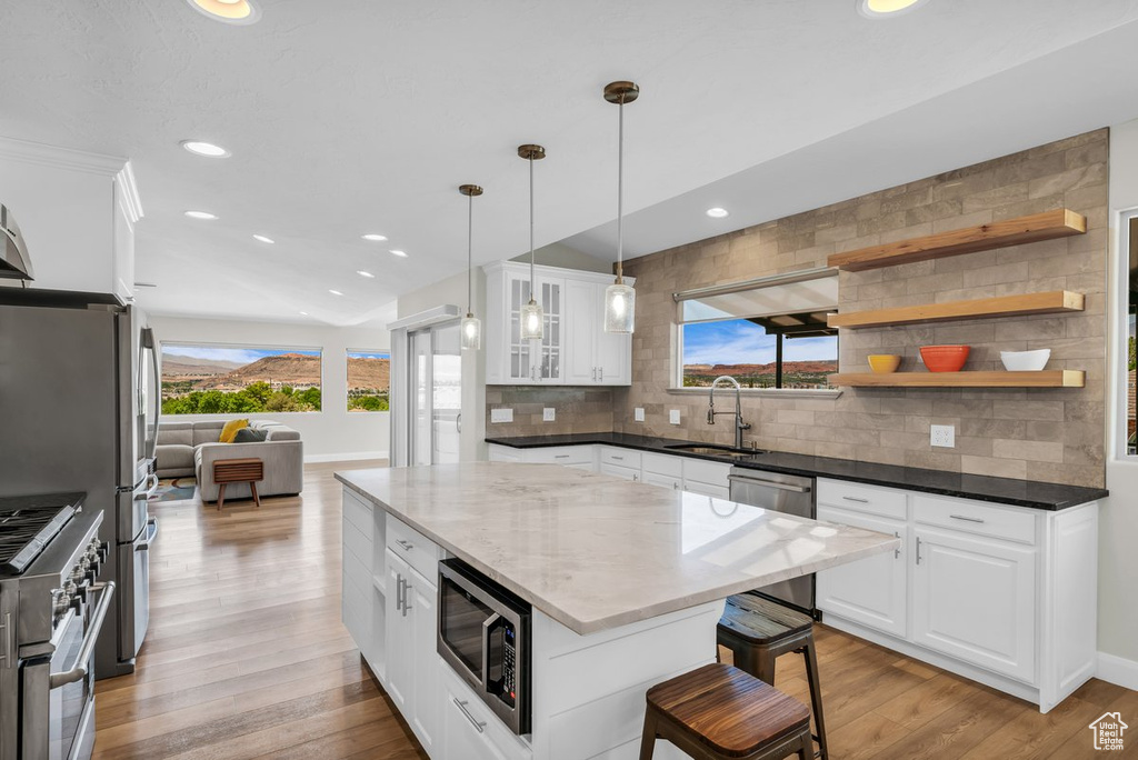 Kitchen with a sink, appliances with stainless steel finishes, backsplash, a breakfast bar area, and recessed lighting