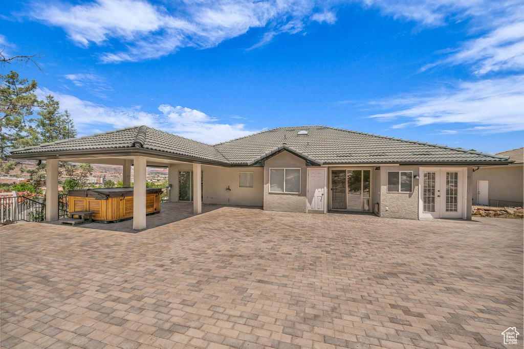 Rear view of property featuring a hot tub, french doors, a tiled roof, and a patio area