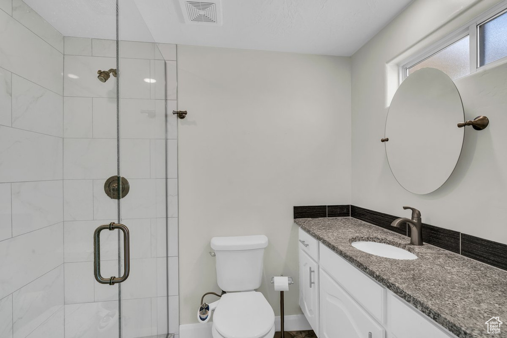 Full bathroom with toilet, vanity, and a stall shower