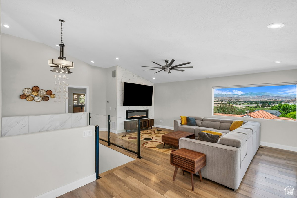 Living room featuring vaulted ceiling, baseboards, recessed lighting, light wood finished floors, and ceiling fan