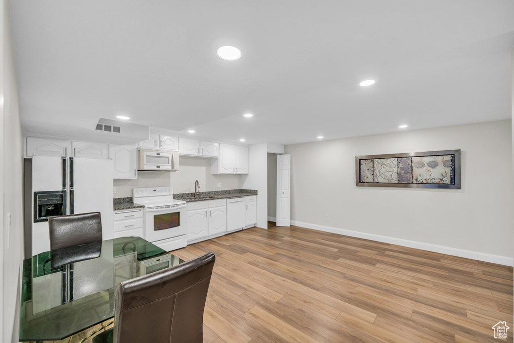 Kitchen with white appliances, white cabinetry, baseboards, recessed lighting, and light wood-style flooring