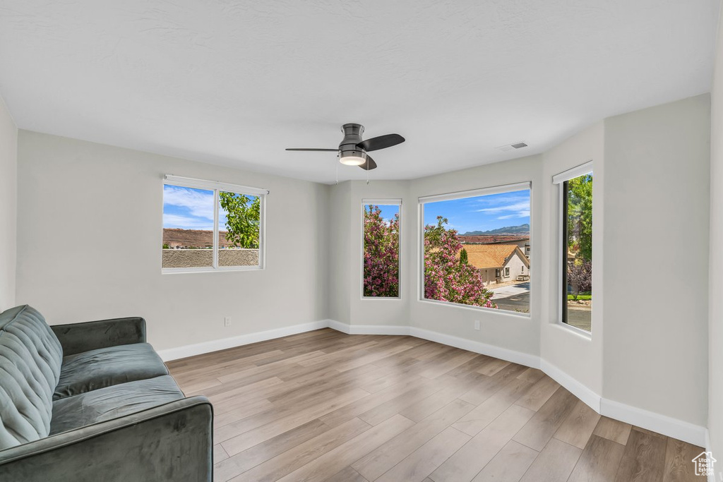 Unfurnished room with healthy amount of natural light, light wood-type flooring, baseboards, and ceiling fan