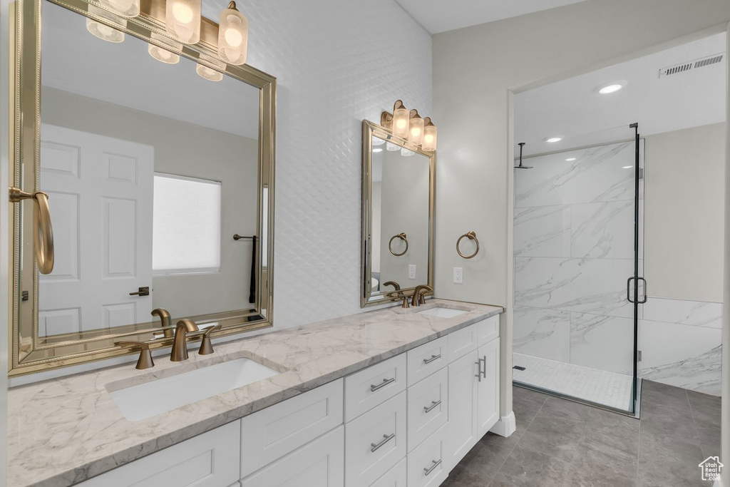 Full bathroom with a marble finish shower and double vanity