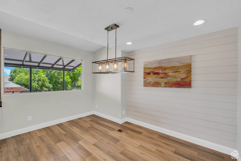 Unfurnished room with baseboards, wood finished floors, wooden walls, and recessed lighting