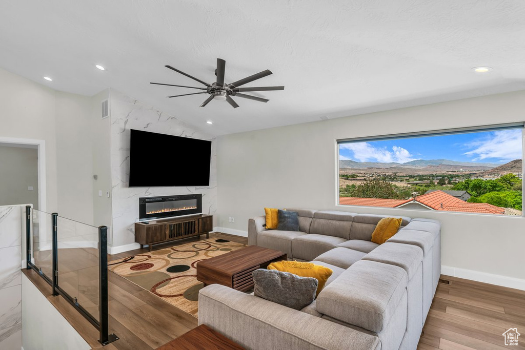 Living area featuring light wood-type flooring, ceiling fan, recessed lighting, baseboards, and a fireplace