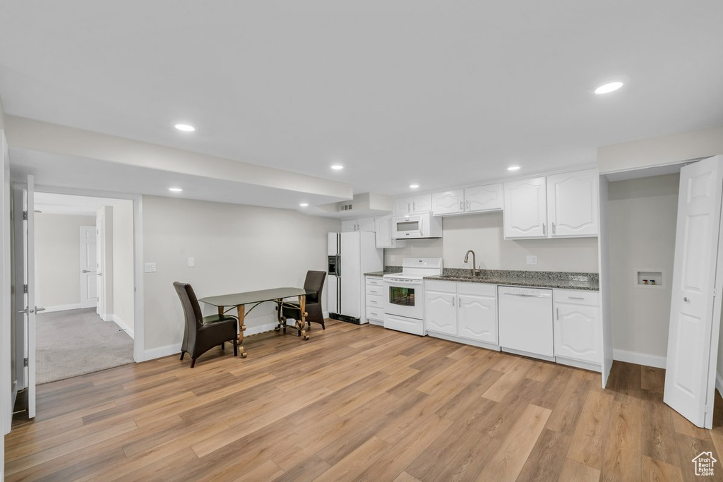 Kitchen featuring white appliances, a sink, white cabinets, light wood-style flooring, and recessed lighting