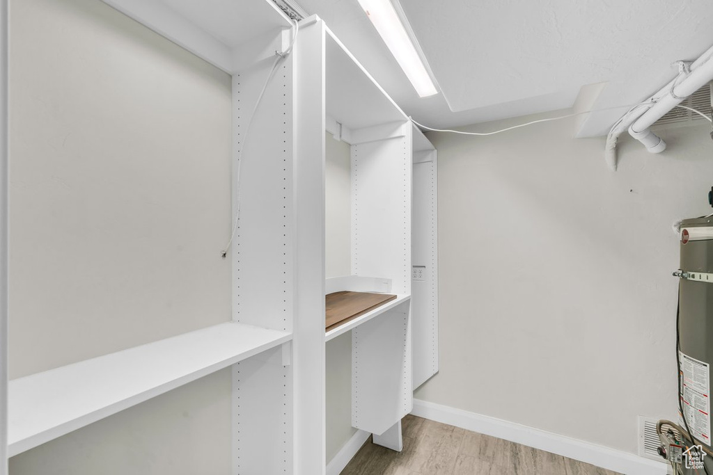 Walk in closet featuring wood finished floors and water heater