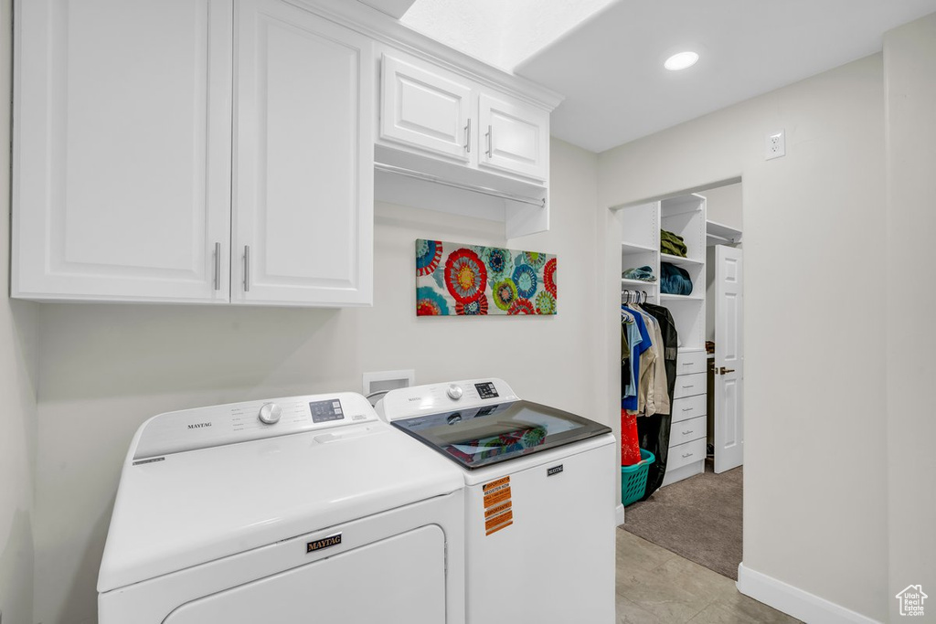 Washroom with cabinet space, washer and clothes dryer, and baseboards