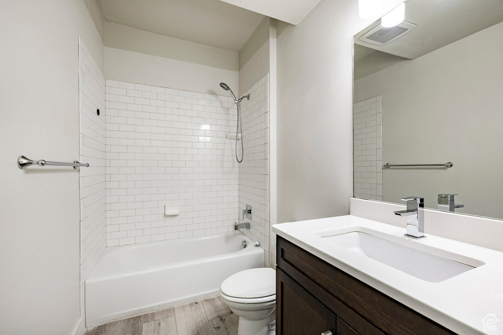 Bathroom with wood finished floors, vanity, toilet, and shower / tub combination