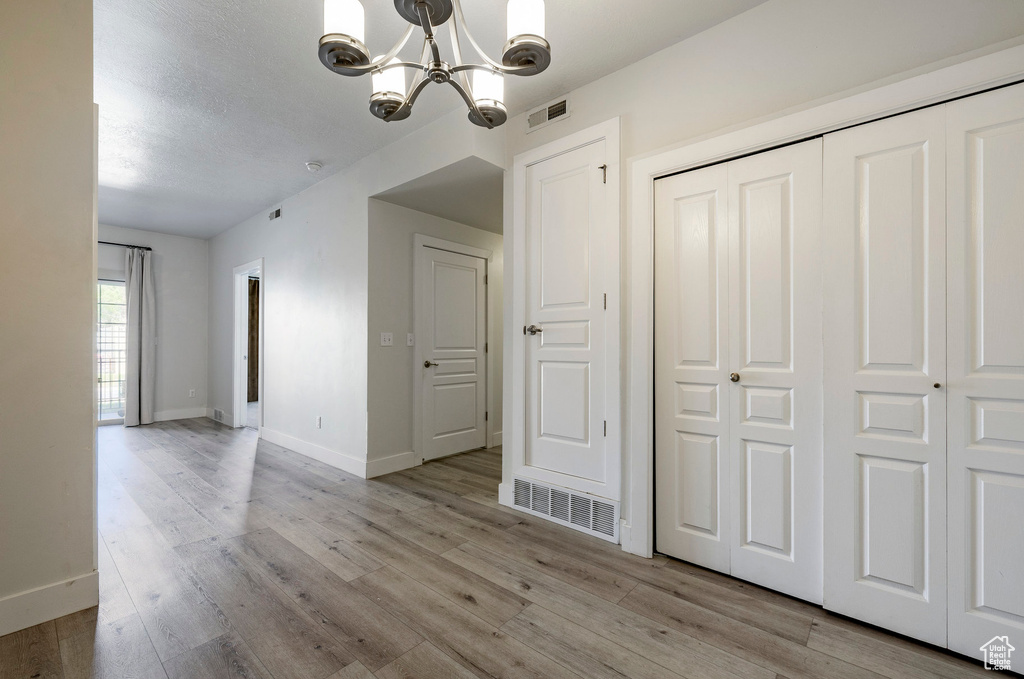 Unfurnished dining area with a chandelier, baseboards, and light wood-style flooring