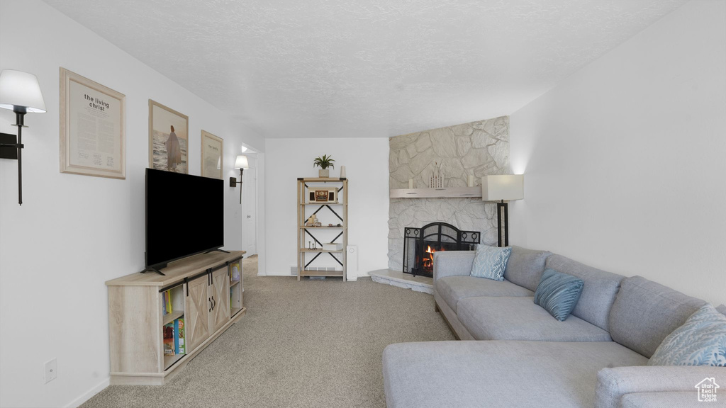 Carpeted living area with a fireplace, a textured ceiling, and baseboards