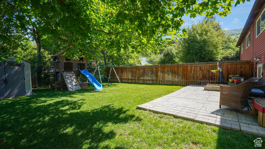 View of yard with a patio area, a playground, and a storage shed