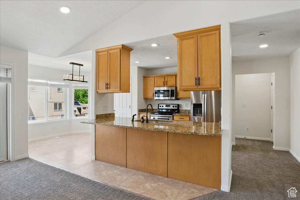 Kitchen featuring stainless steel appliances, a sink, light carpet, dark stone countertops, and vaulted ceiling