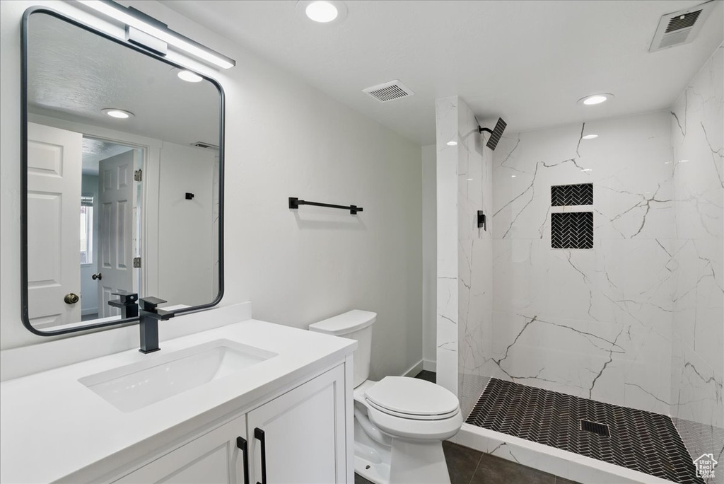 Full bath featuring toilet, vanity, a marble finish shower, recessed lighting, and tile patterned floors