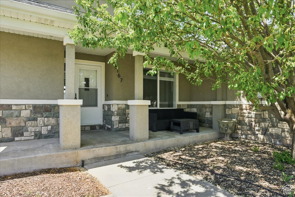 Property entrance featuring stone siding, a porch, and stucco siding