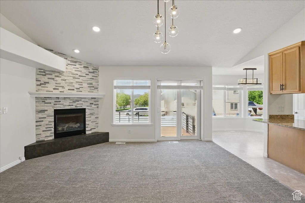 Unfurnished living room with lofted ceiling, a fireplace, carpet, baseboards, and recessed lighting