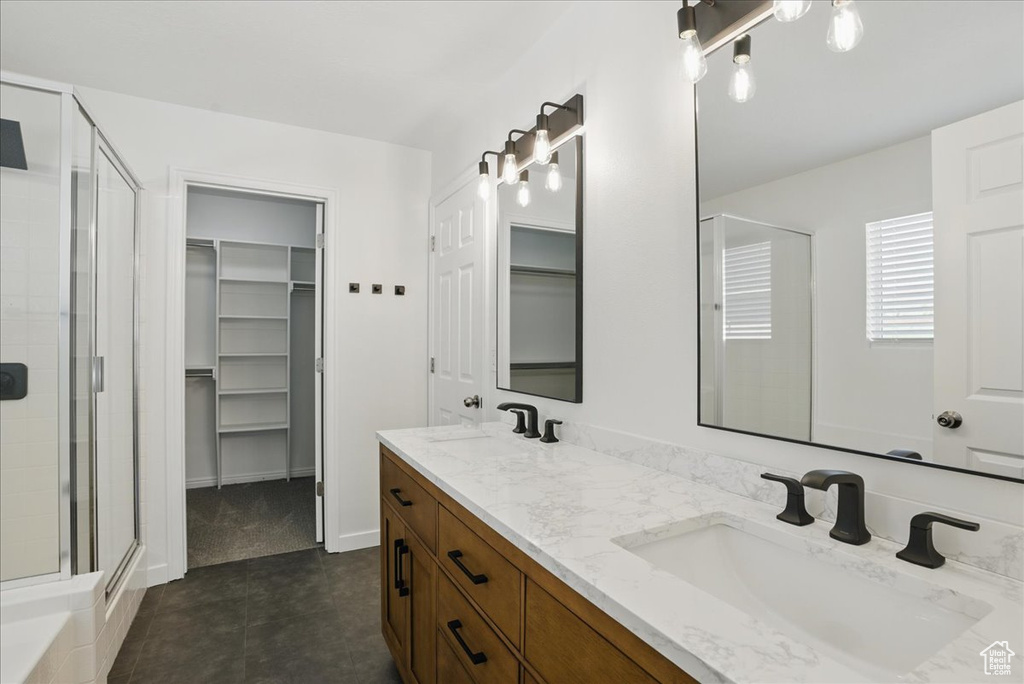 Full bathroom featuring a stall shower, a walk in closet, double vanity, and tile patterned floors