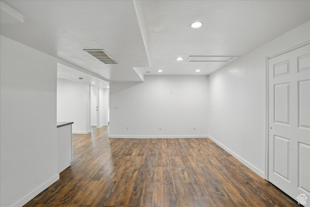 Below grade area with dark wood-type flooring, baseboards, recessed lighting, and a textured ceiling