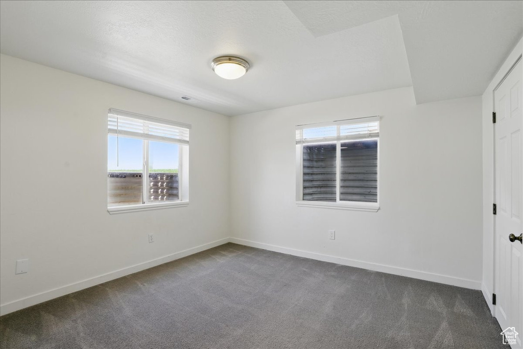 Unfurnished bedroom featuring dark carpet and baseboards