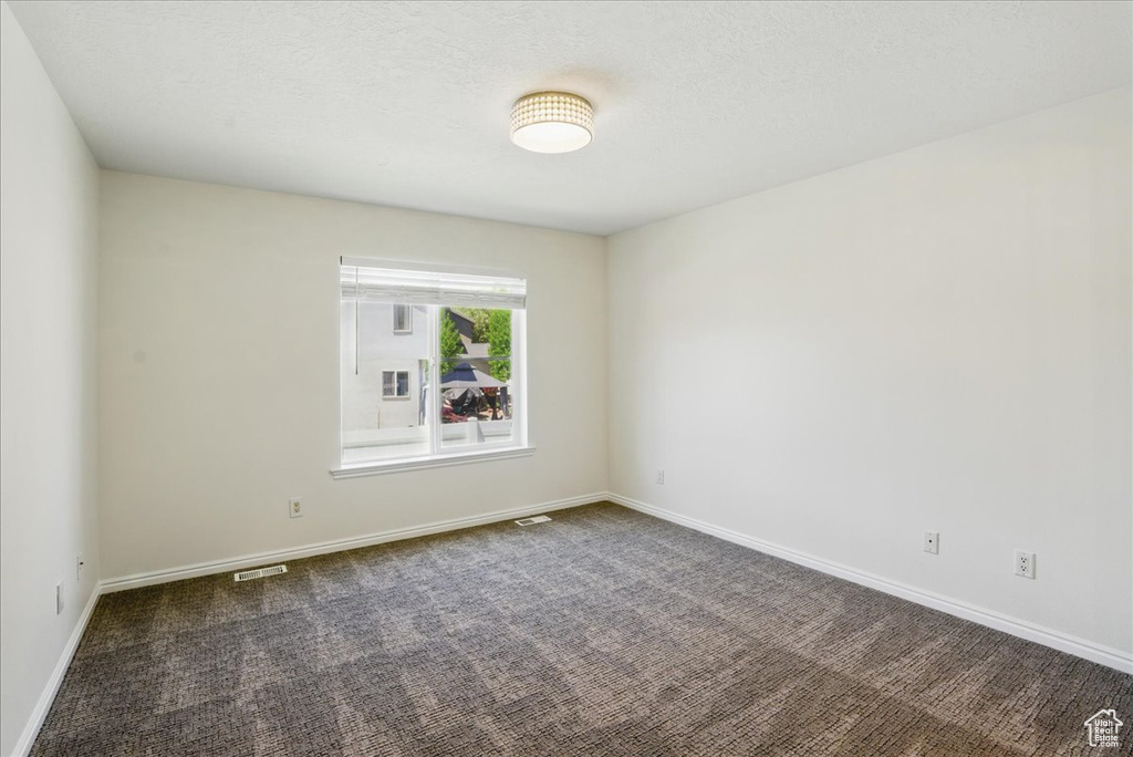 Spare room featuring dark carpet and baseboards