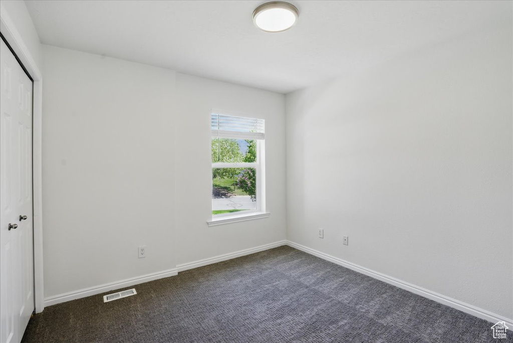 Unfurnished bedroom featuring dark colored carpet, a closet, and baseboards