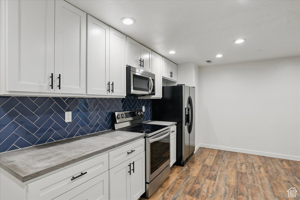 Kitchen featuring appliances with stainless steel finishes, baseboards, backsplash, white cabinets, and recessed lighting